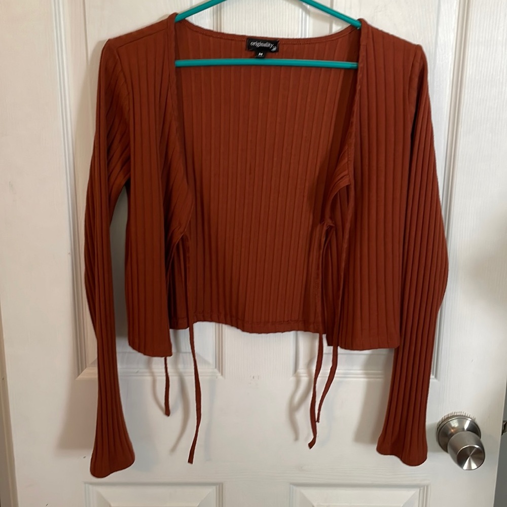 Burnt orange cropped cardigan with double ties in the middle.